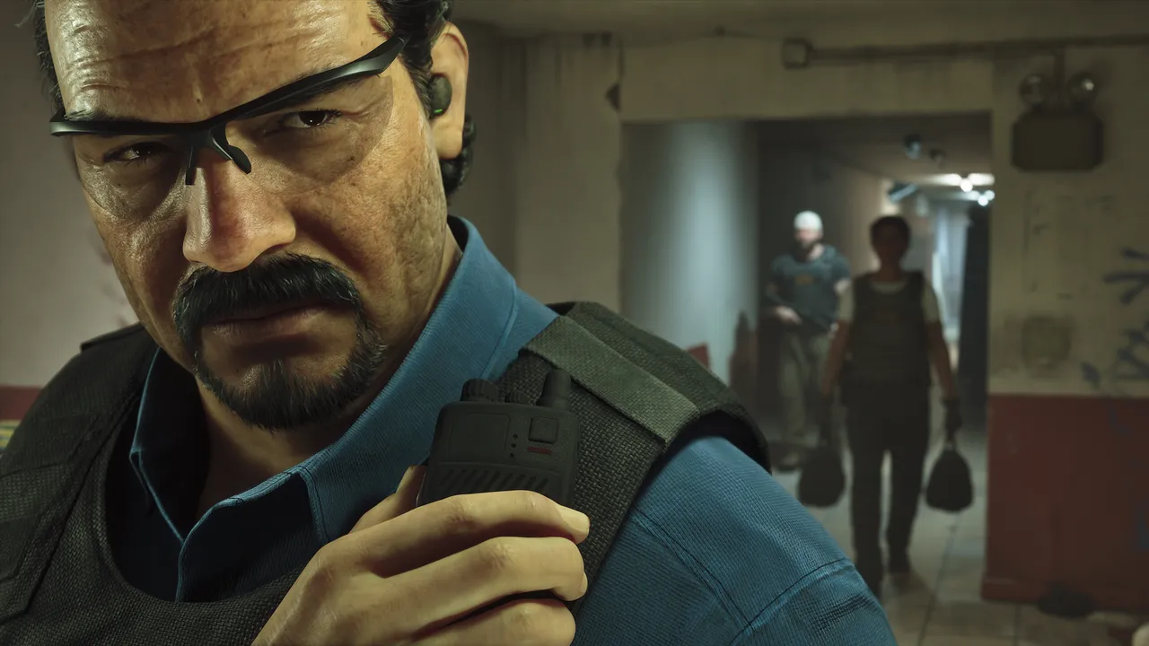 Close-up of a man in a vest holding a radio, with two armed figures in the hallway behind him