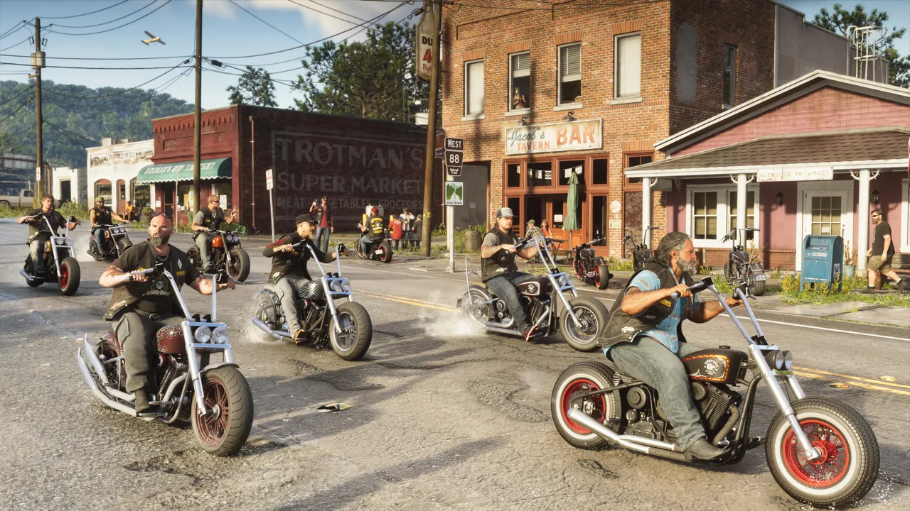 A pack of bikers riding through a small-town main street past a bar and a supermarket